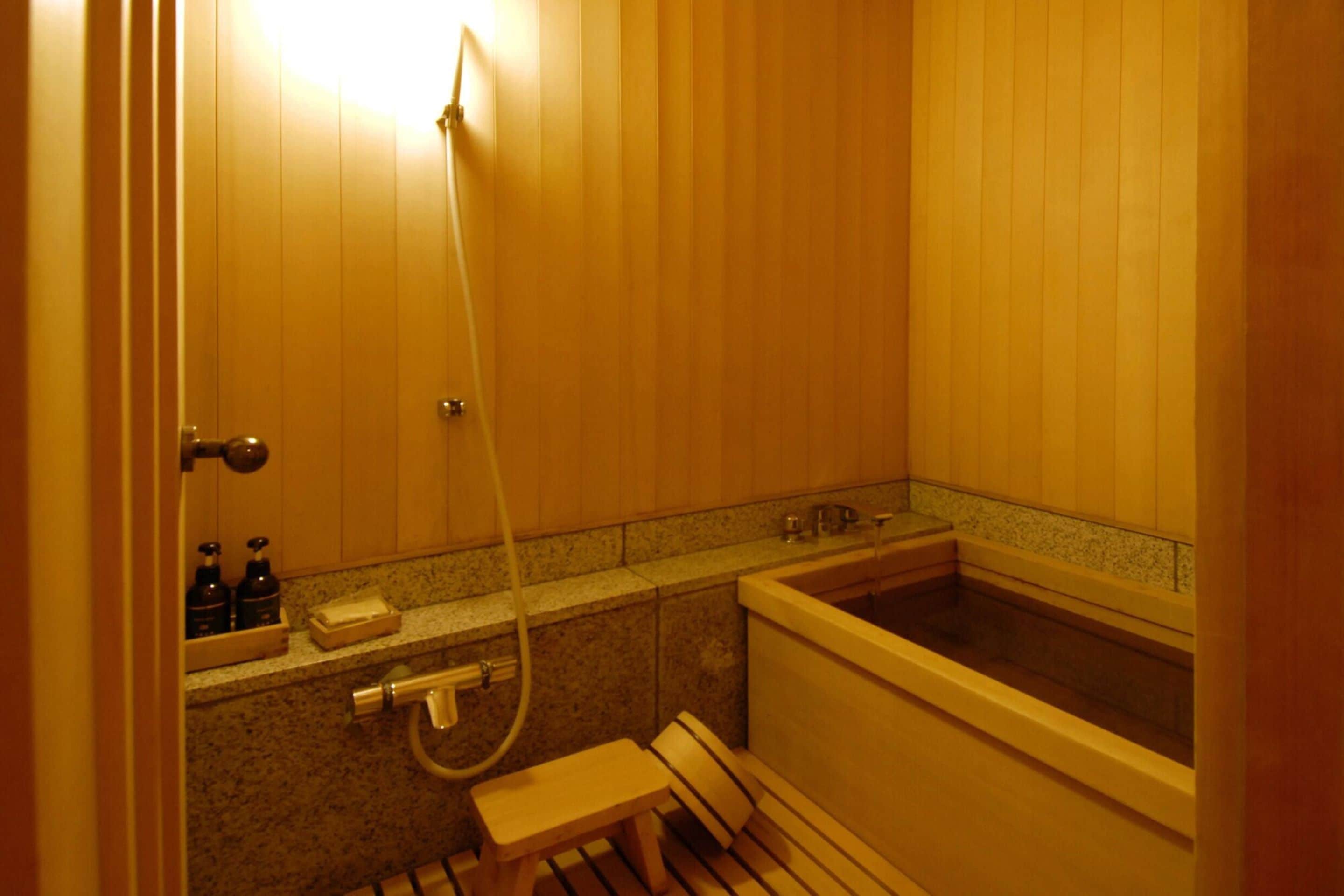 A wooden bathroom with a bathtub, a shower, and a bench.