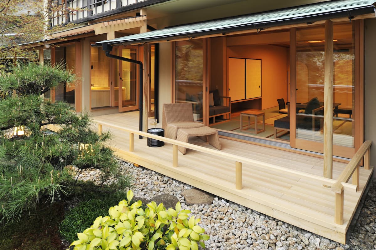 Una casa moderna de estilo japonés con terraza de madera, puertas corredizas de vidrio y una sala tradicional con tatami.