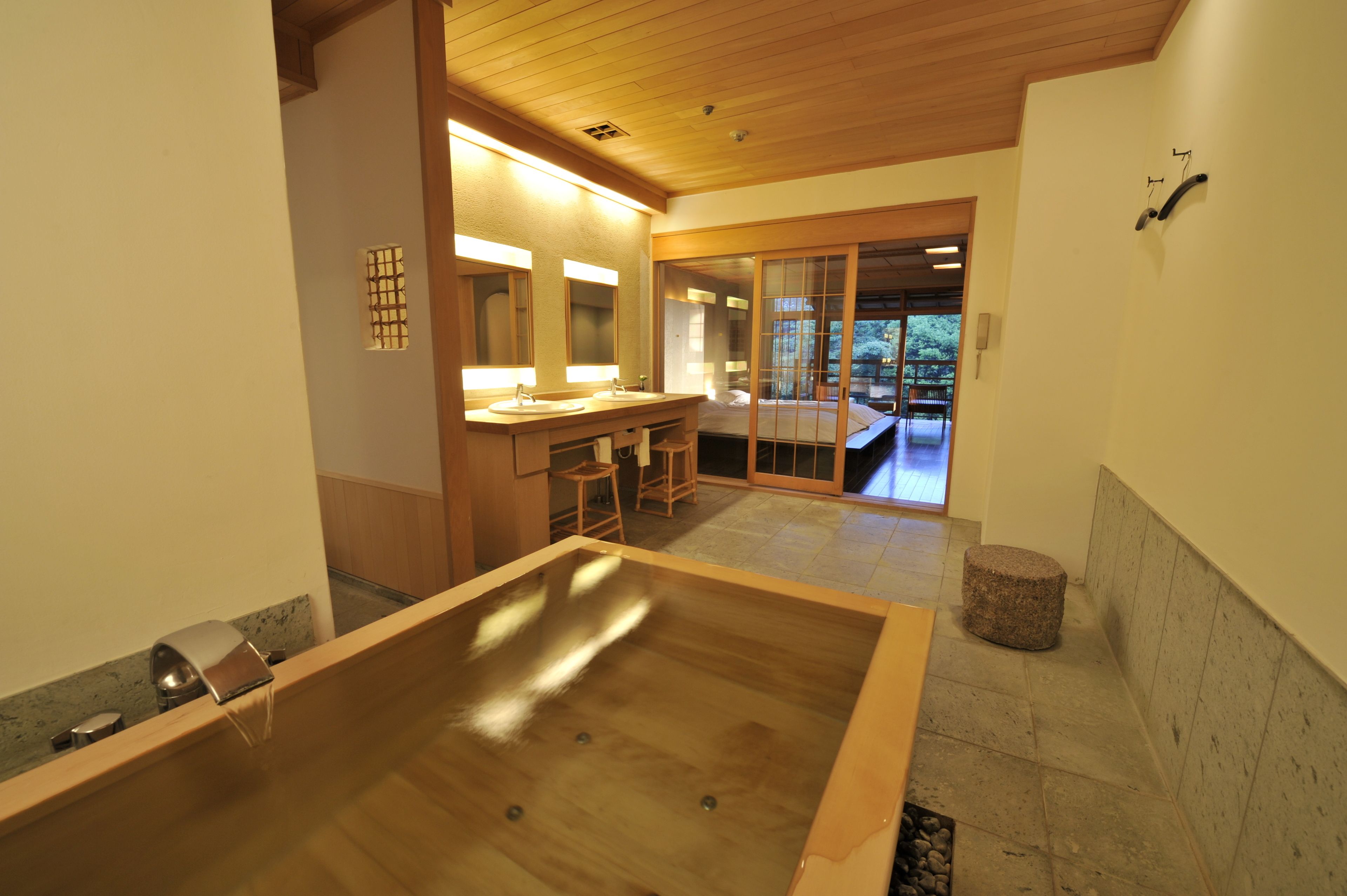 A modern bathroom with a wooden bathtub, a sink, and a large mirror.