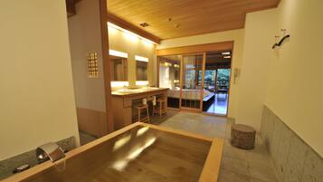 A modern bathroom with a wooden bathtub, a sink, and a large mirror.