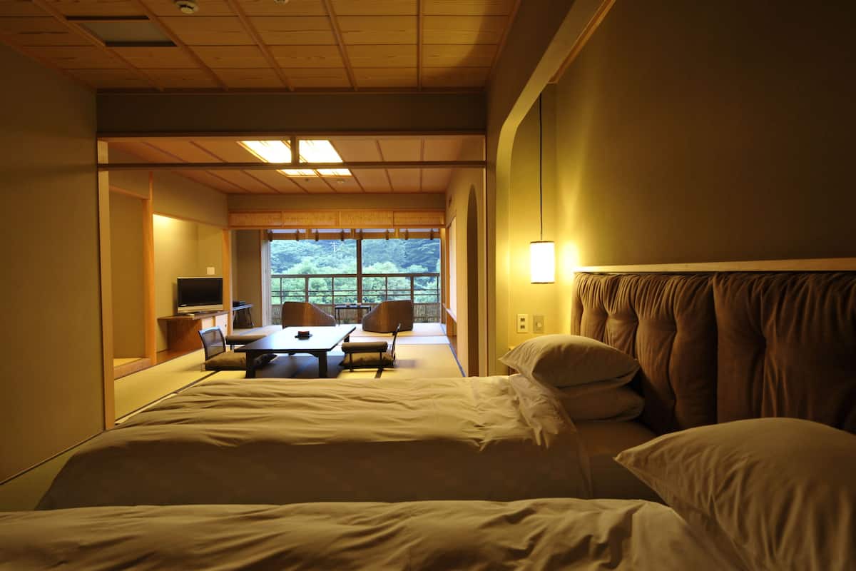 Una habitación de hotel con una cama, un escritorio, sillas y un televisor.