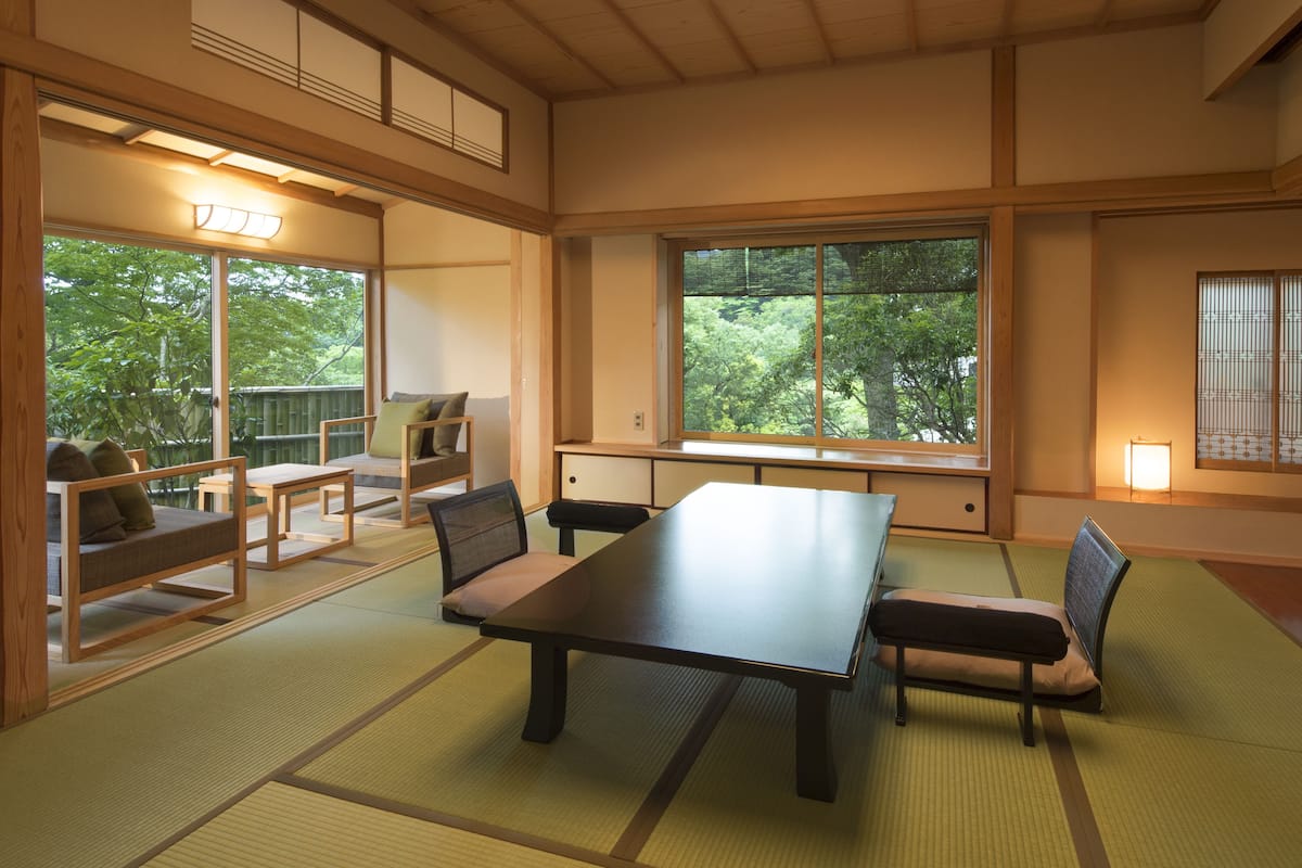 Una habitación tradicional japonesa con suelo de tatami, una mesa baja y disposición de asientos.