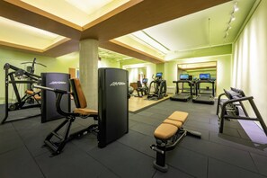 A gym with various exercise equipment including weight machines, treadmills, and a bench.