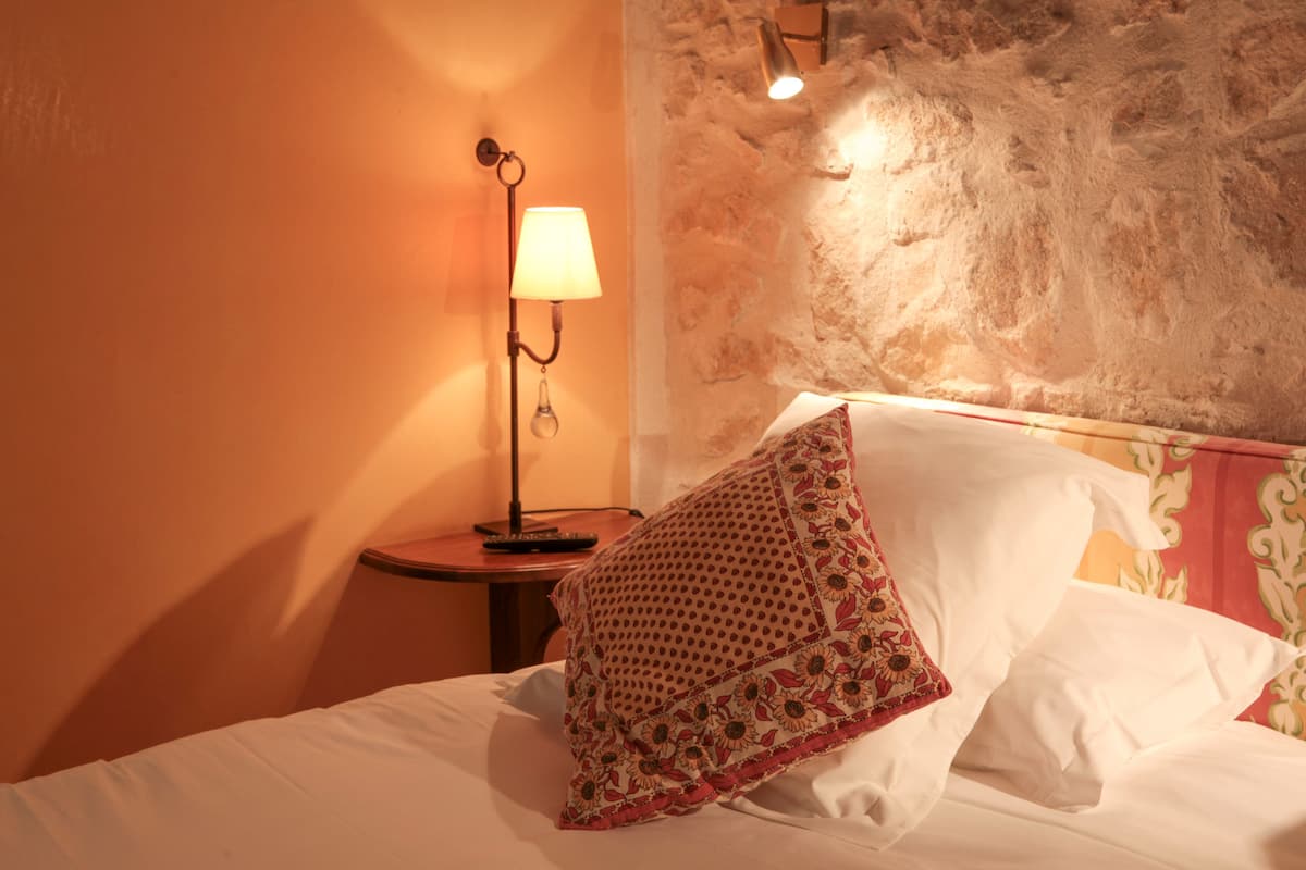 A hotel room with a bed, a lamp, and a textured wall.