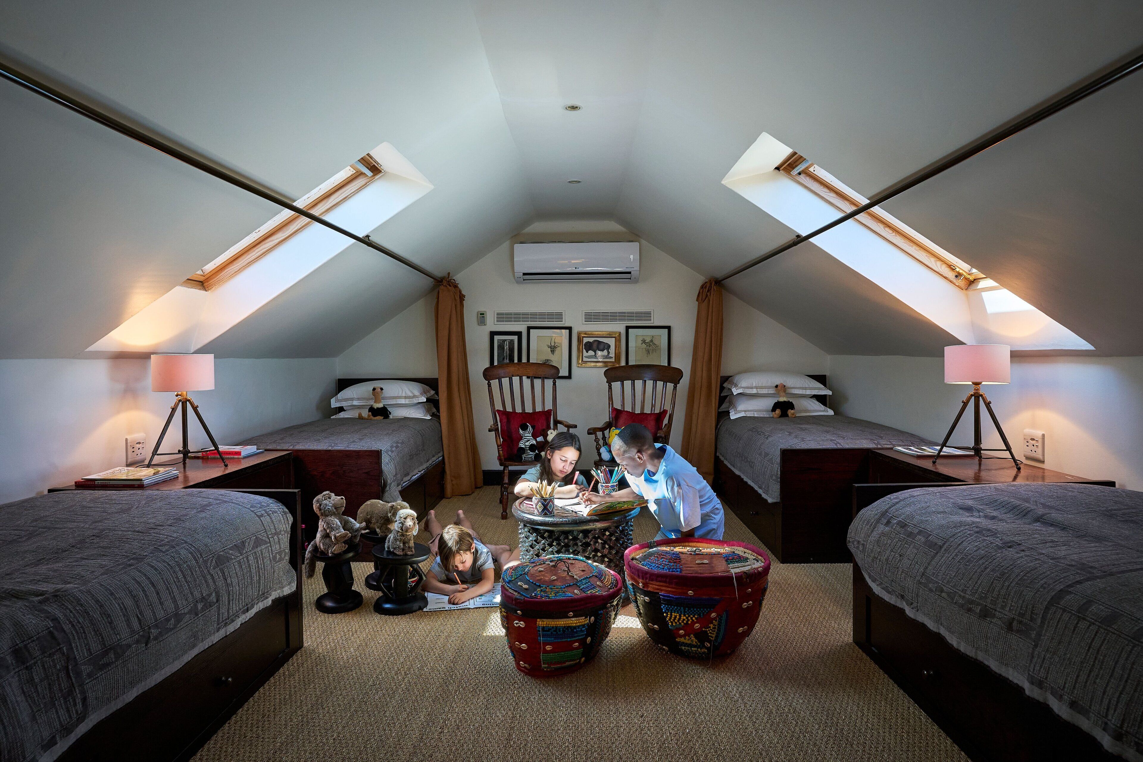 A bedroom with two beds, a skylight, and a central table with chairs.