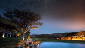 Un espace extérieur avec une piscine, une table et des chaises, le tout sous un ciel étoilé.
