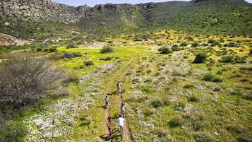 Paisaje montañoso con un sendero de tierra y ciclistas.