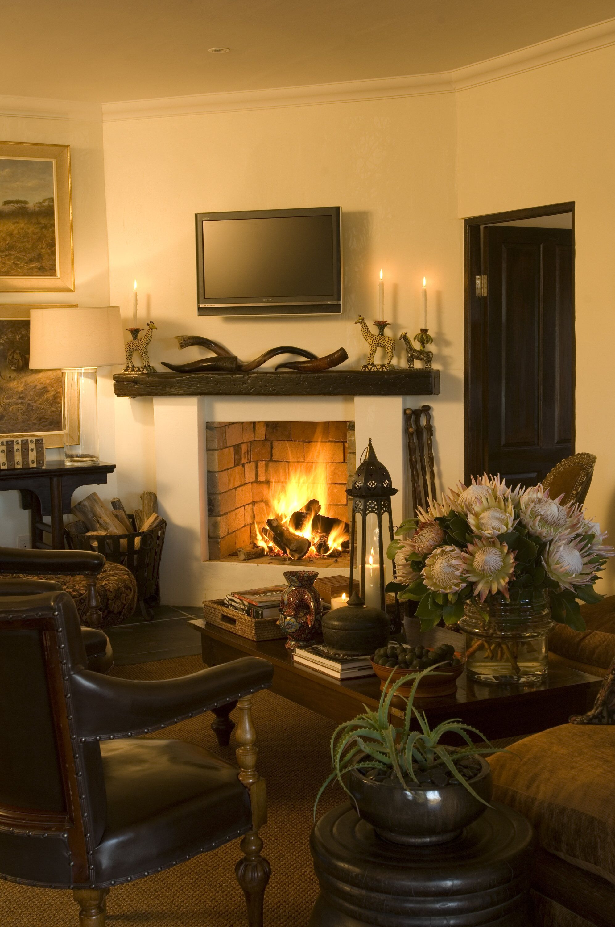 Una sala de estar acogedora con chimenea, un televisor montado encima y un área de descanso con una butaca y un sofá.