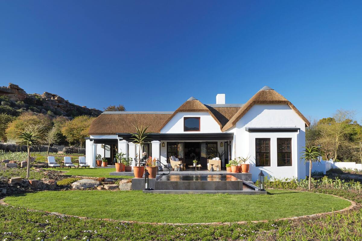 Une maison moderne dotée d’une grande pelouse à l’avant, d’un espace salon extérieur et d’une piscine.