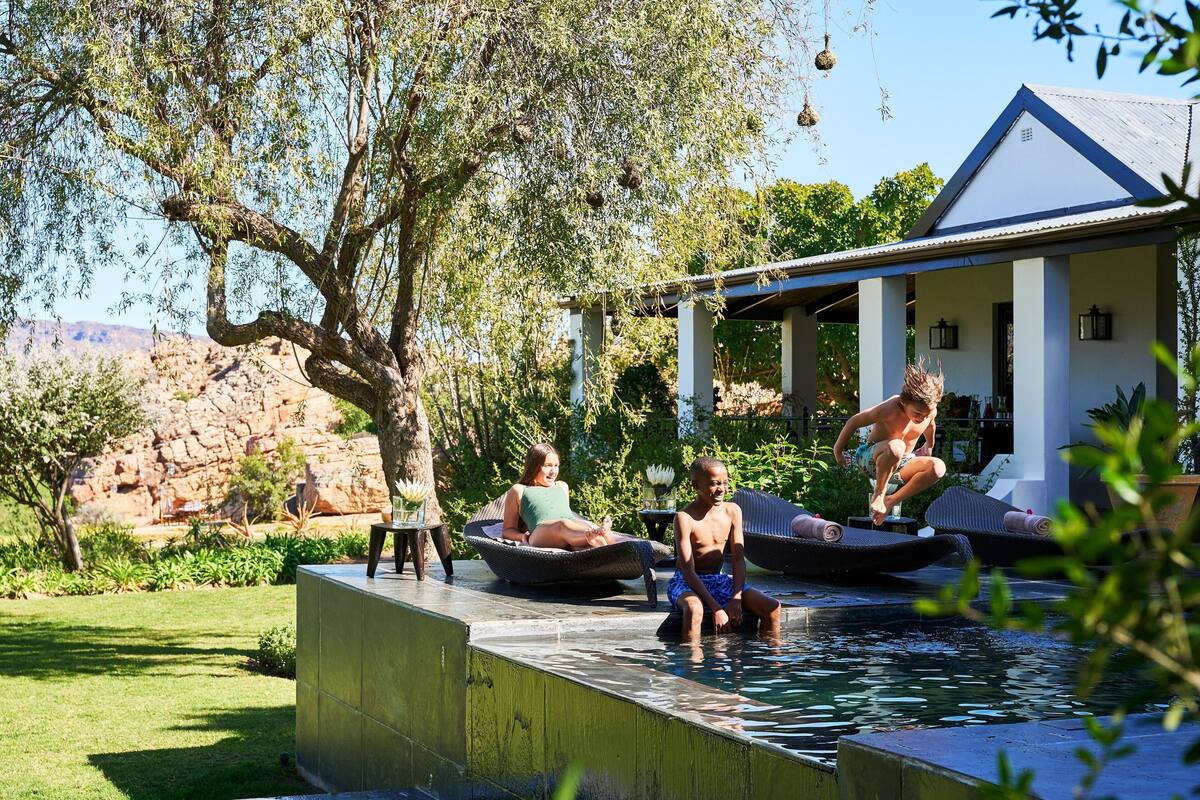 Une piscine entourée de chaises longues, avec une maison en arrière-plan.