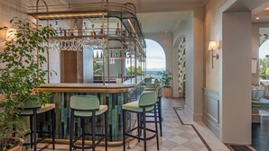 A bar area with a curved counter, multiple bar stools, and a wine rack with glasses.