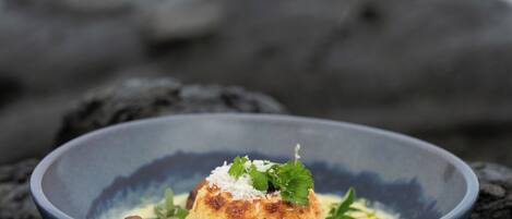 A bowl of food on a dark surface with a blurred background of rocks and water.