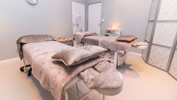 Experience serene relaxation in this tranquil treatment room, featuring two massage tables and a peaceful atmosphere.