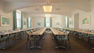 A conference room with long tables, chairs, and framed artwork on the walls.