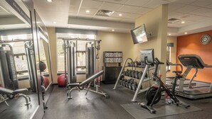 A gym with various exercise equipment, including treadmills, weight machines, and dumbbells.
