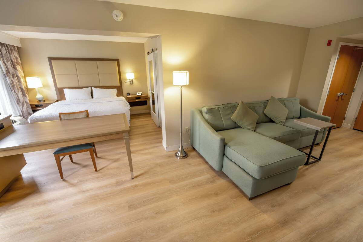 Une chambre d’hôtel avec un lit, un canapé, un bureau et une lampe.