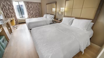 Habitación de hotel con dos camas, un escritorio, una silla y un ventanal grande.