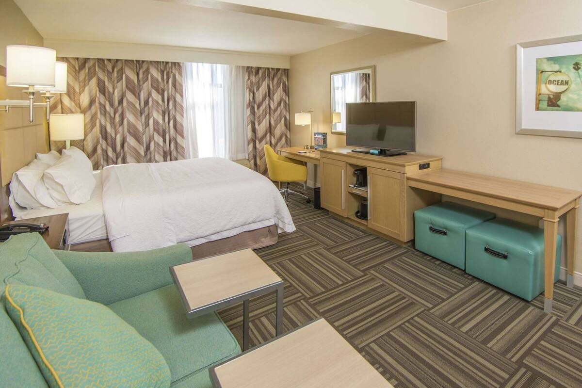 Une chambre d’hôtel équipée d’un lit, d’un bureau, d’une télévision, d’un canapé et d’une machine à café.