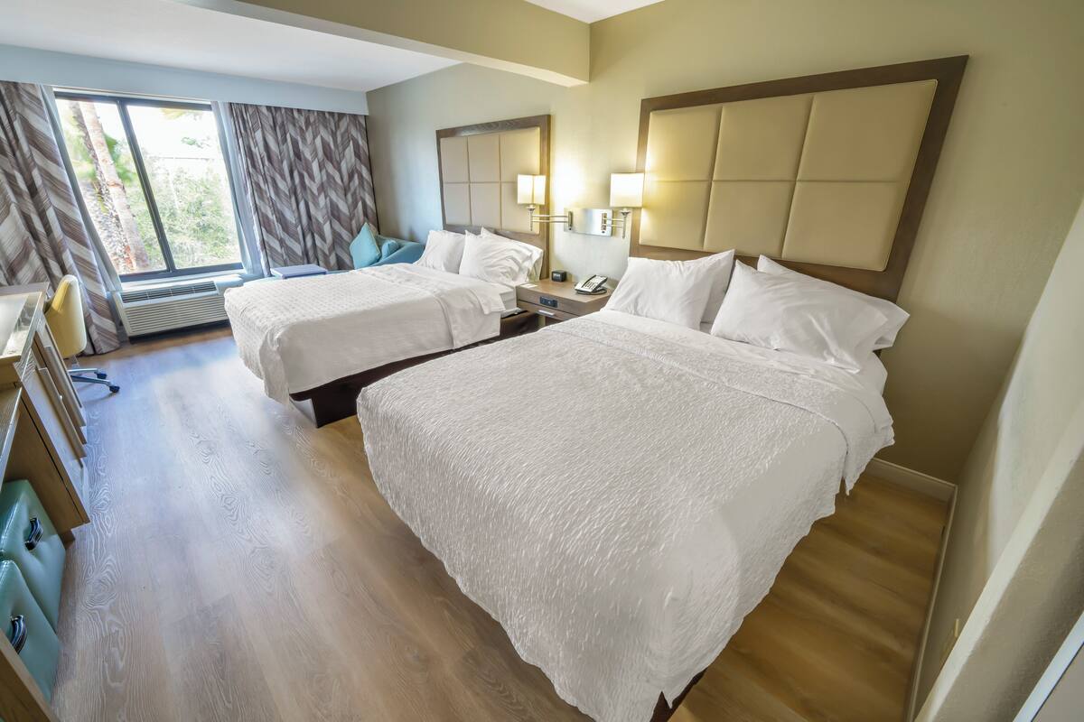 Une chambre d’hôtel avec deux lits, un bureau et une chaise.