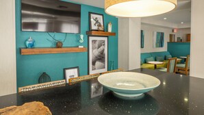 A modern kitchen with a black countertop, a teal backsplash, and a large hanging light fixture.