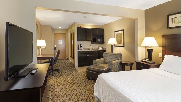 A hotel room with a bed, desk, TV, kitchenette, and seating area. - Holiday Inn Express Bloomington West by IHG (Bloomington)