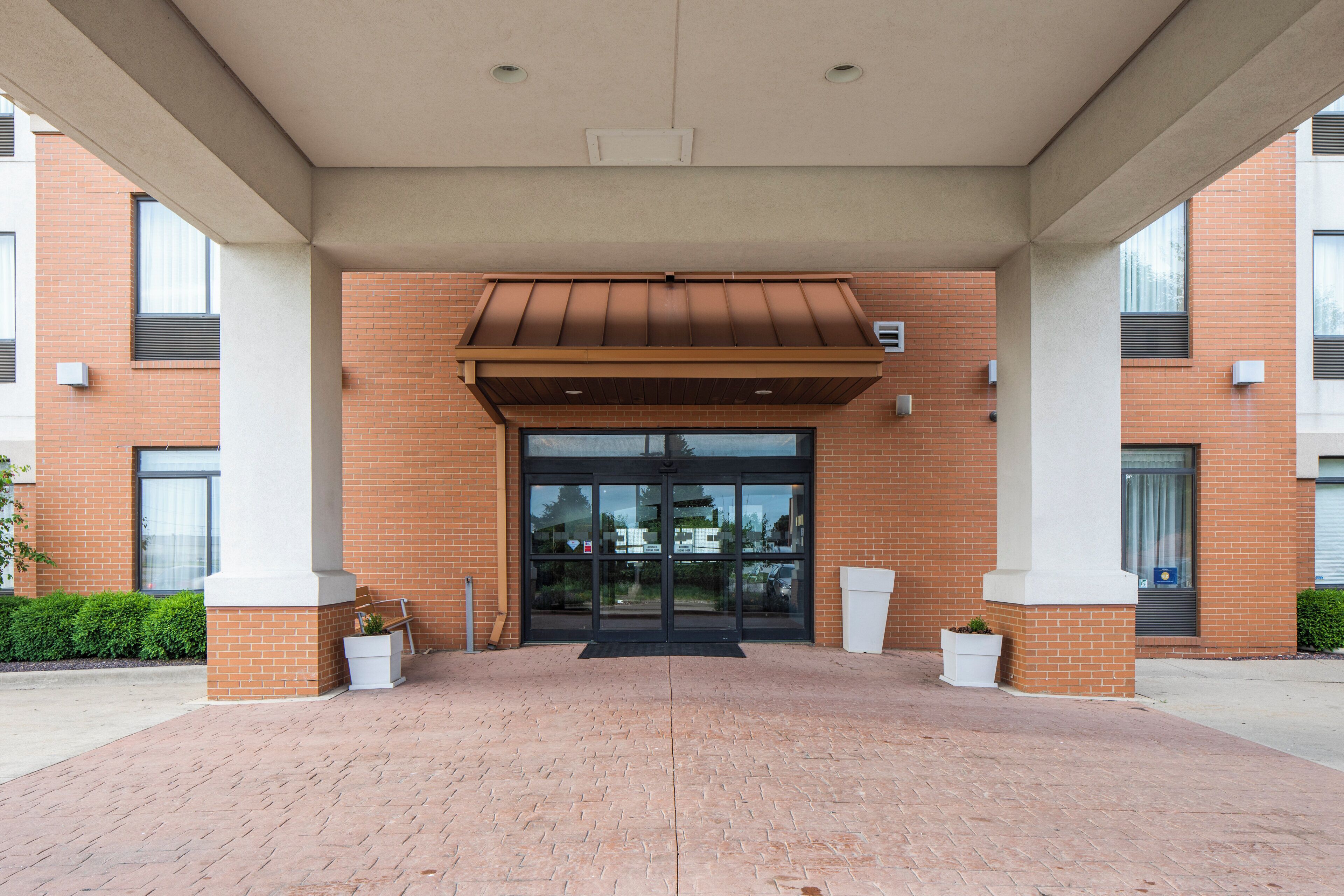 A building entrance with a brick facade, a metal awning, and a glass door.