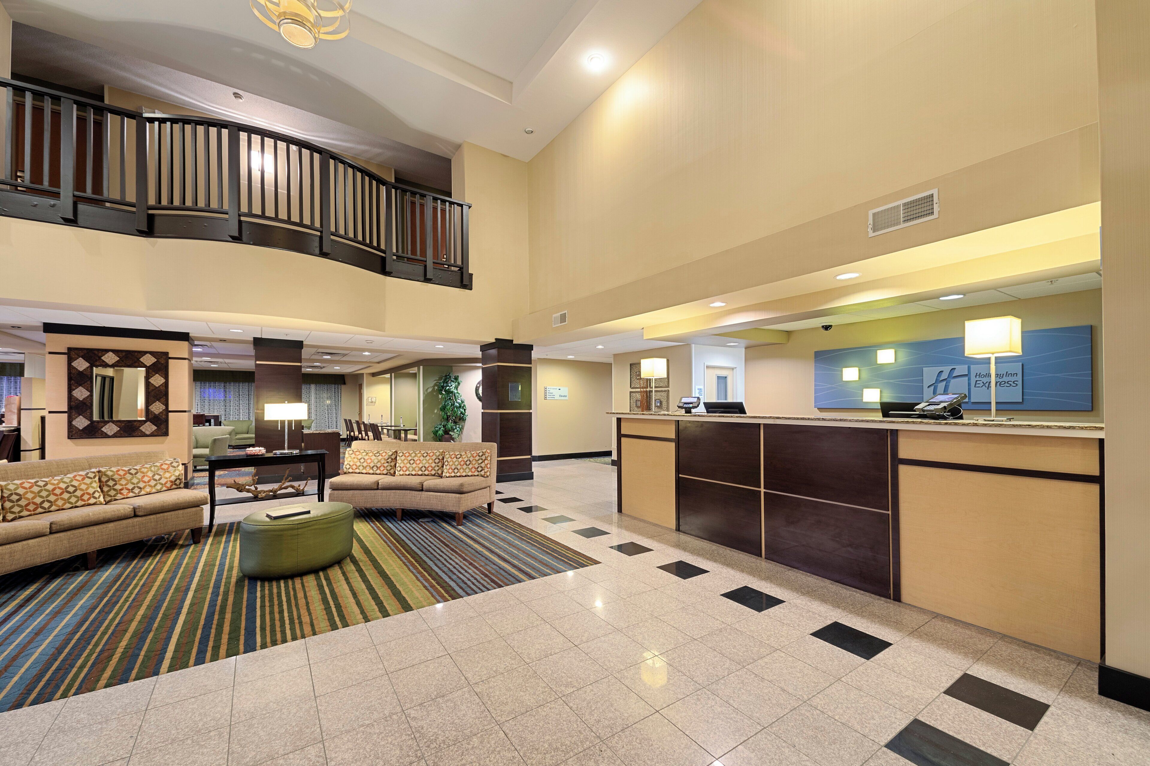 A hotel lobby with a reception desk, seating area, and a staircase.