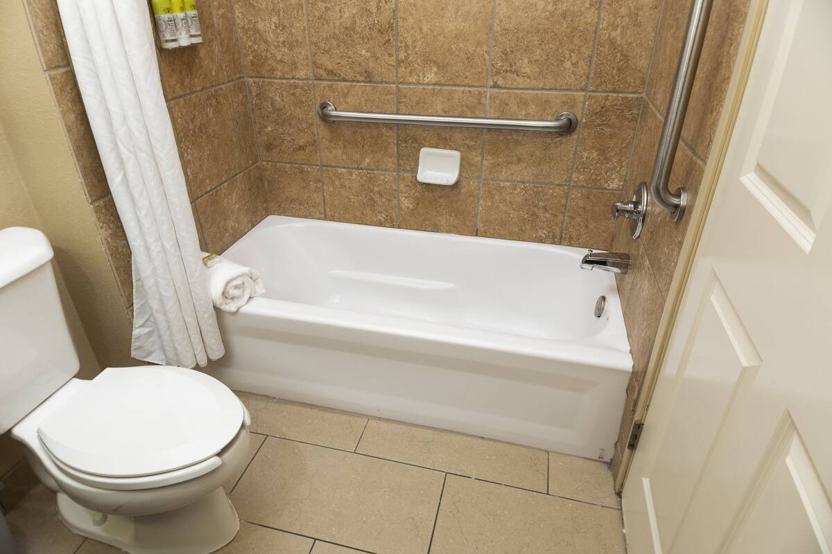 A bathroom with a white toilet, a bathtub, and a shower area.