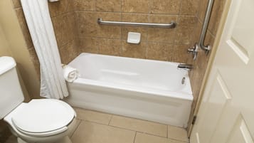 A bathroom with a white toilet, a bathtub, and a shower area.