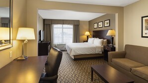 Ein Hotelzimmer mit Bett, Schreibtisch, Stuhl, Sofa und Fernseher.