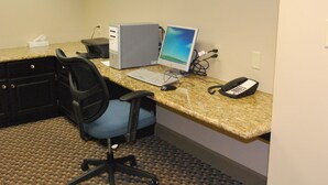 Ein Hotelbüro mit einem Desktop-Computer, einem Laptop, einem Telefon und einem Stuhl.