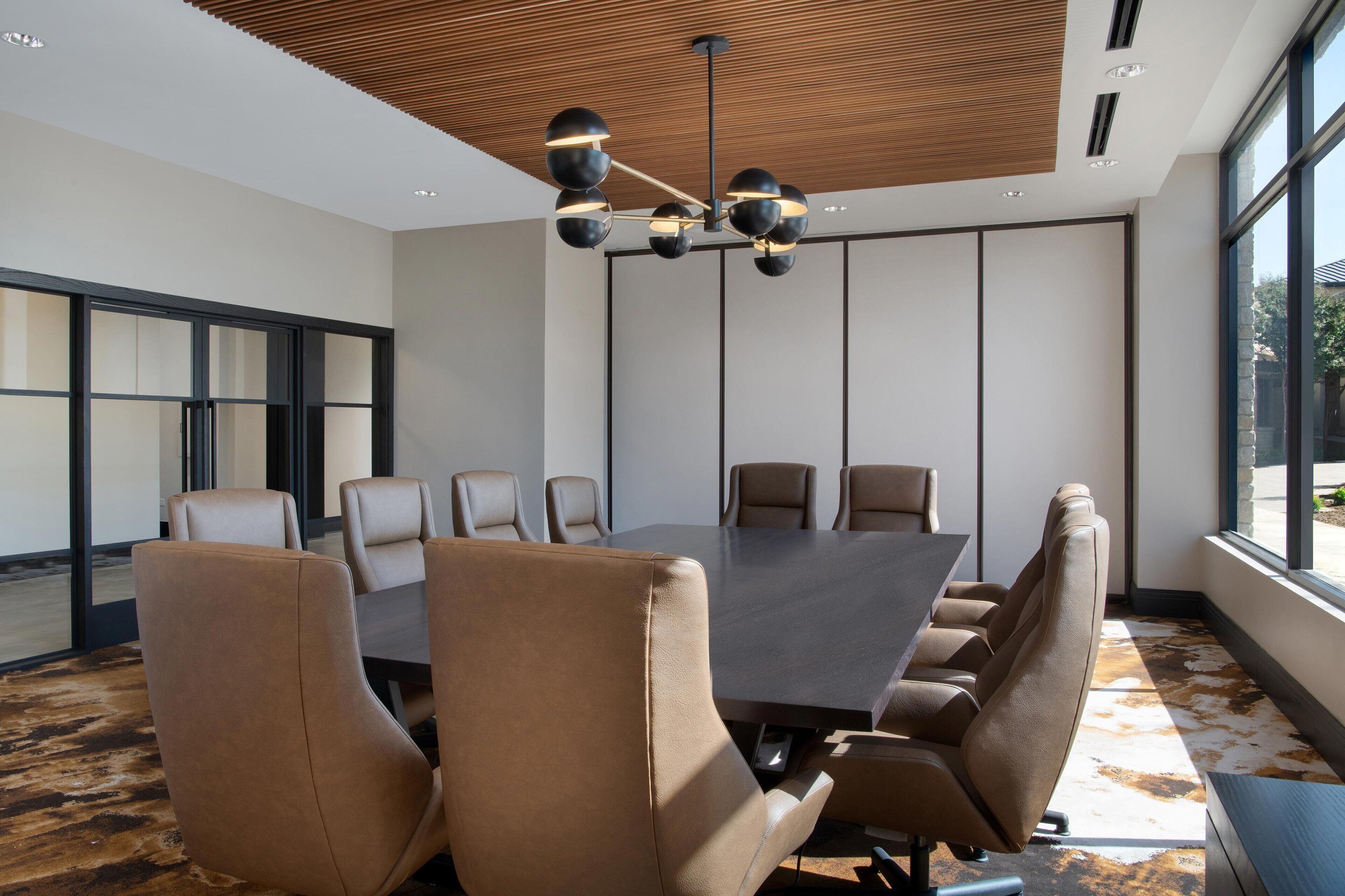 Une salle de conférence dotée d’une grande table et de nombreuses chaises, d’un design de plafond moderne et de grandes fenêtres.