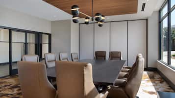 Une salle de conférence dotée d’une grande table et de nombreuses chaises, d’un design de plafond moderne et de grandes fenêtres.