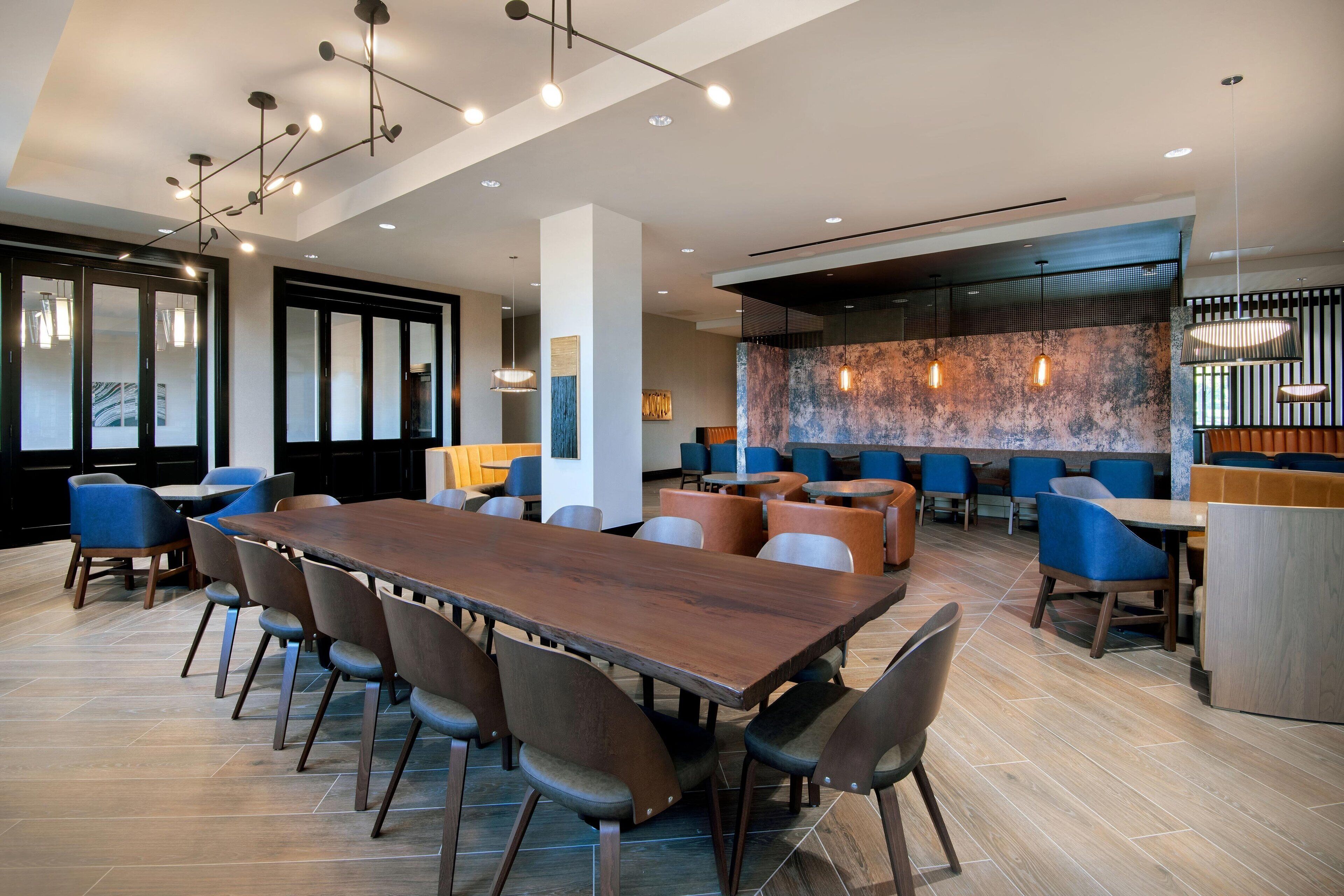Un comedor moderno con una larga mesa de madera y varias sillas, una zona de bar con taburetes y un amplio ventanal con vistas.