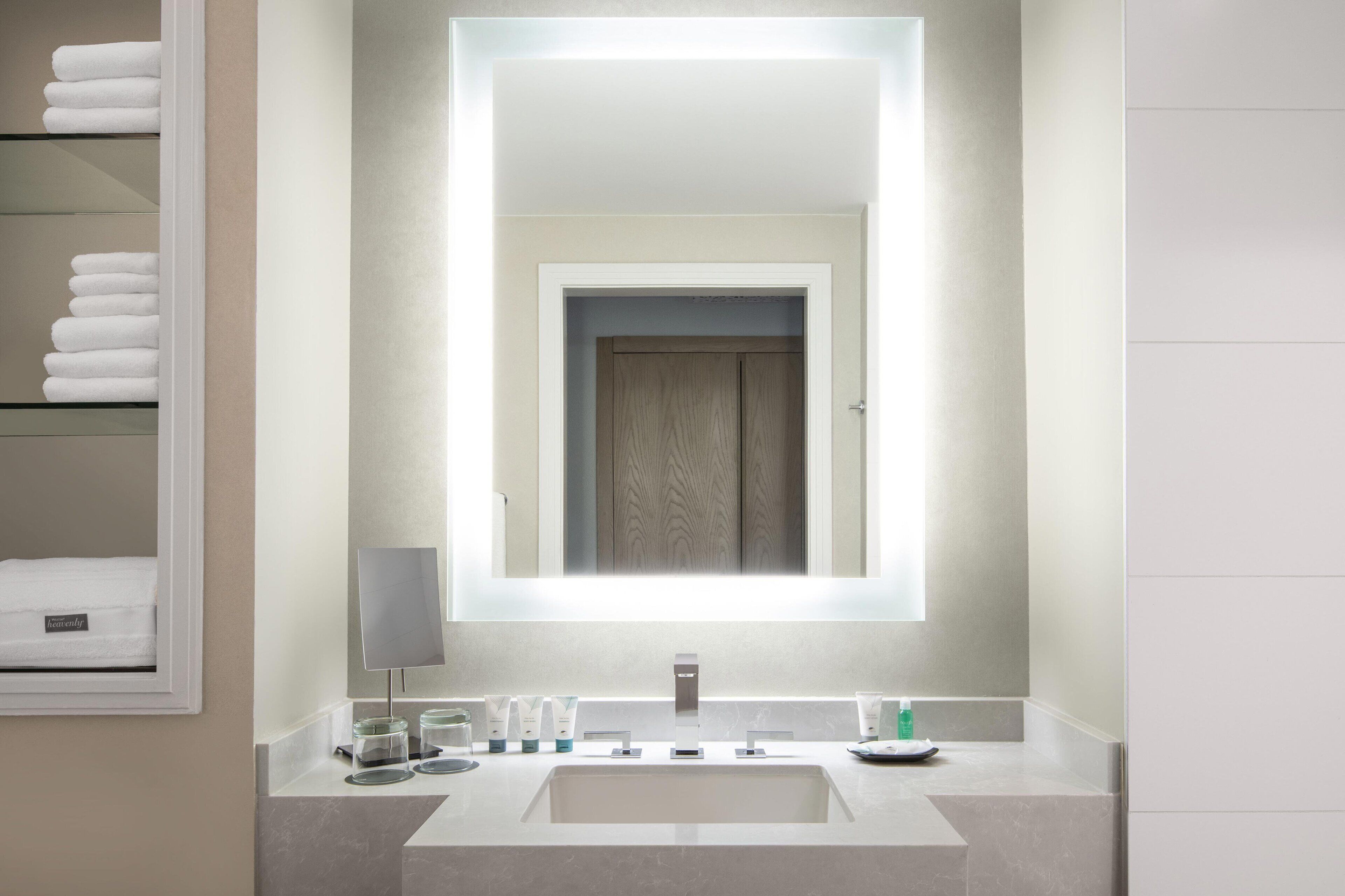 Un baño moderno con un espejo grande, un lavamanos integrado y artículos de tocador ordenados.