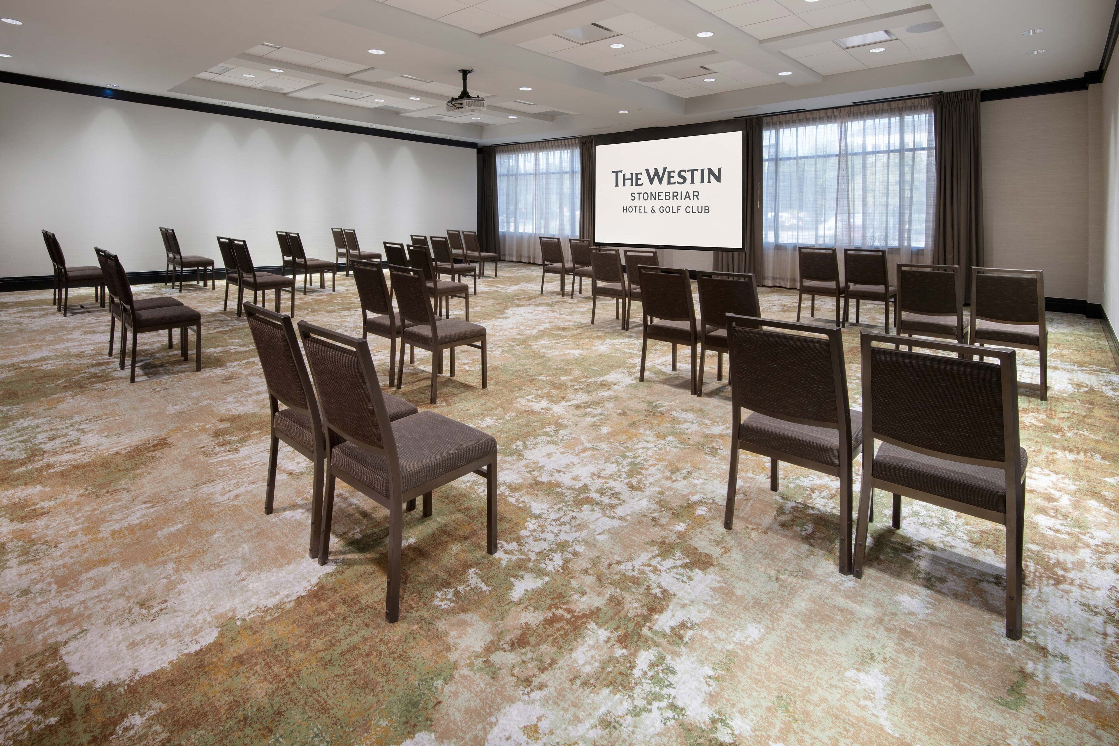 A conference room with rows of chairs and a large screen displaying "The Westin Stonebriar Hotel & Golf Club" name.
