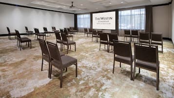 A conference room with rows of chairs and a large screen displaying "The Westin Stonebriar Hotel & Golf Club" name.
