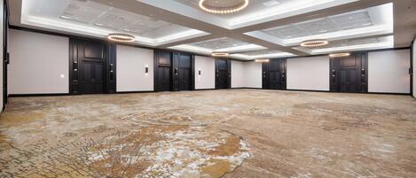 A large, empty conference room with a patterned carpet, multiple doors, and modern ceiling lights.