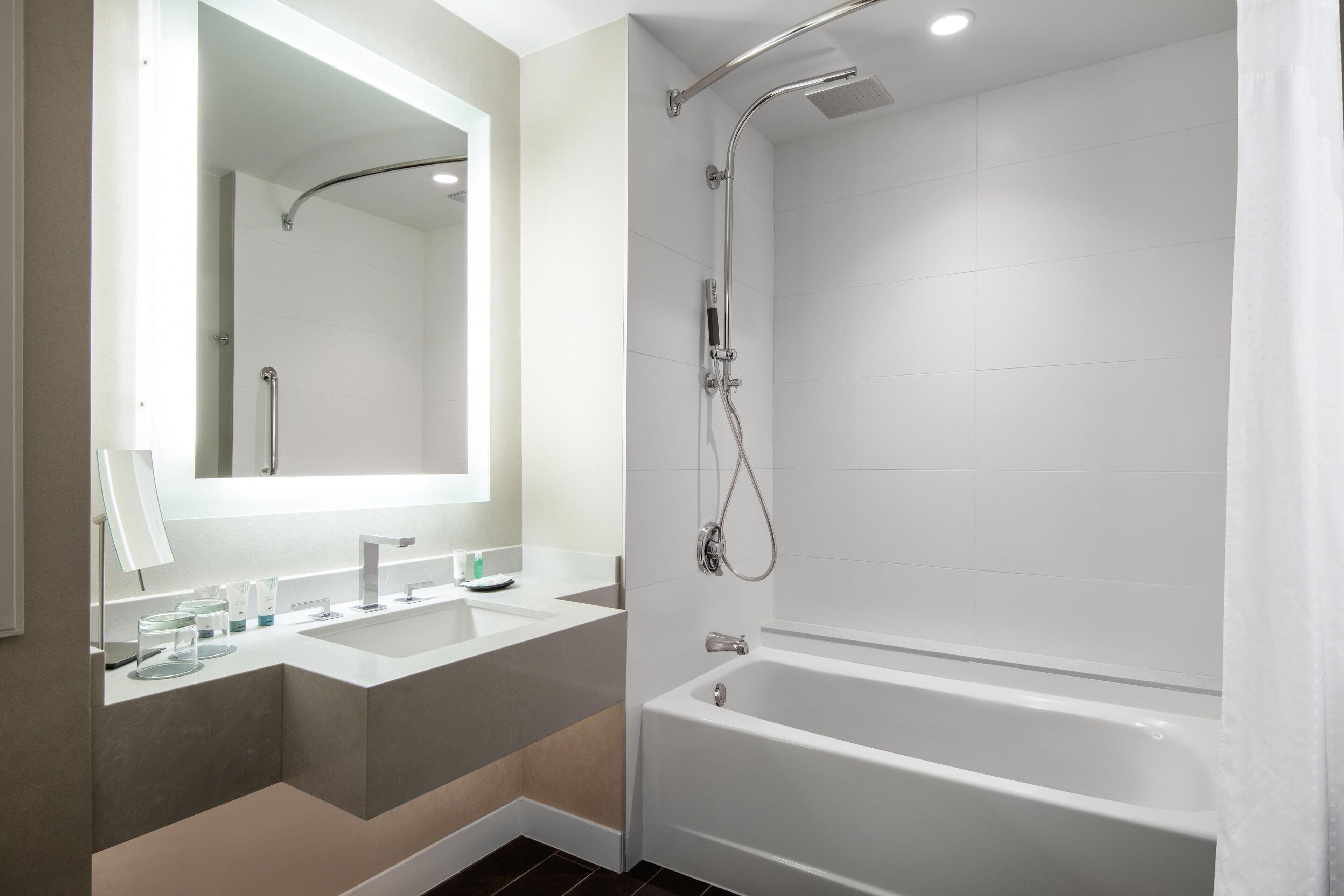Ein modernes Badezimmer mit einem großen Spiegel, zwei Waschbecken, einer Badewanne und einer Dusche.