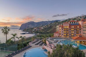 A resort with a large pool, sun loungers, and a view of the ocean and hills. - Pestana Royal All Inclusive Ocean & Spa Resort (Funchal)