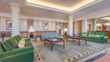 A spacious lobby with a green sofa, a blue sofa, and a wooden coffee table.