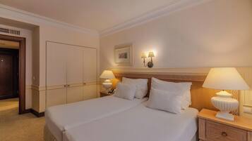 Habitación de hotel con una cama grande, dos mesitas de noche con lámparas, un armario y un cuadro enmarcado en la pared.