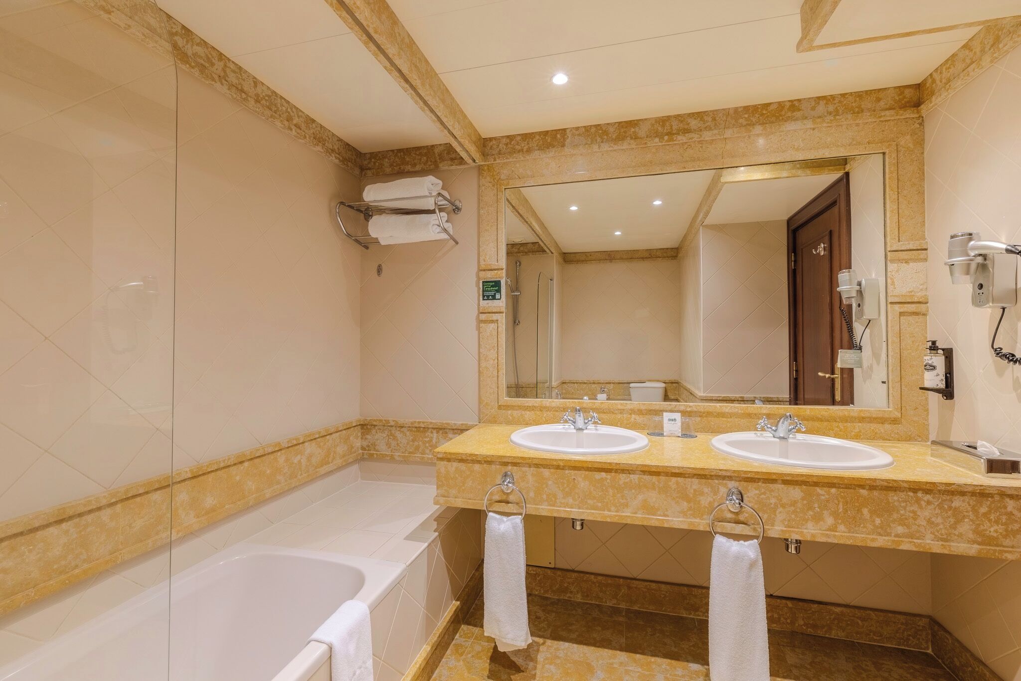 A bathroom with two sinks, a bathtub, and a large mirror.