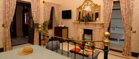 Un dormitorio con cama, chimenea, espejo y televisor.