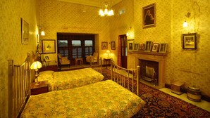 A room with two beds, a fireplace, and a large window. - Gajner Palace (Kolayat)