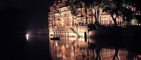 Un edificio histórico con varios niveles y un reflejo en el agua.