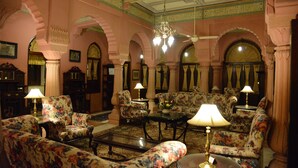 A room with floral-patterned sofas, a coffee table, and lamps. - Gajner Palace (Kolayat)