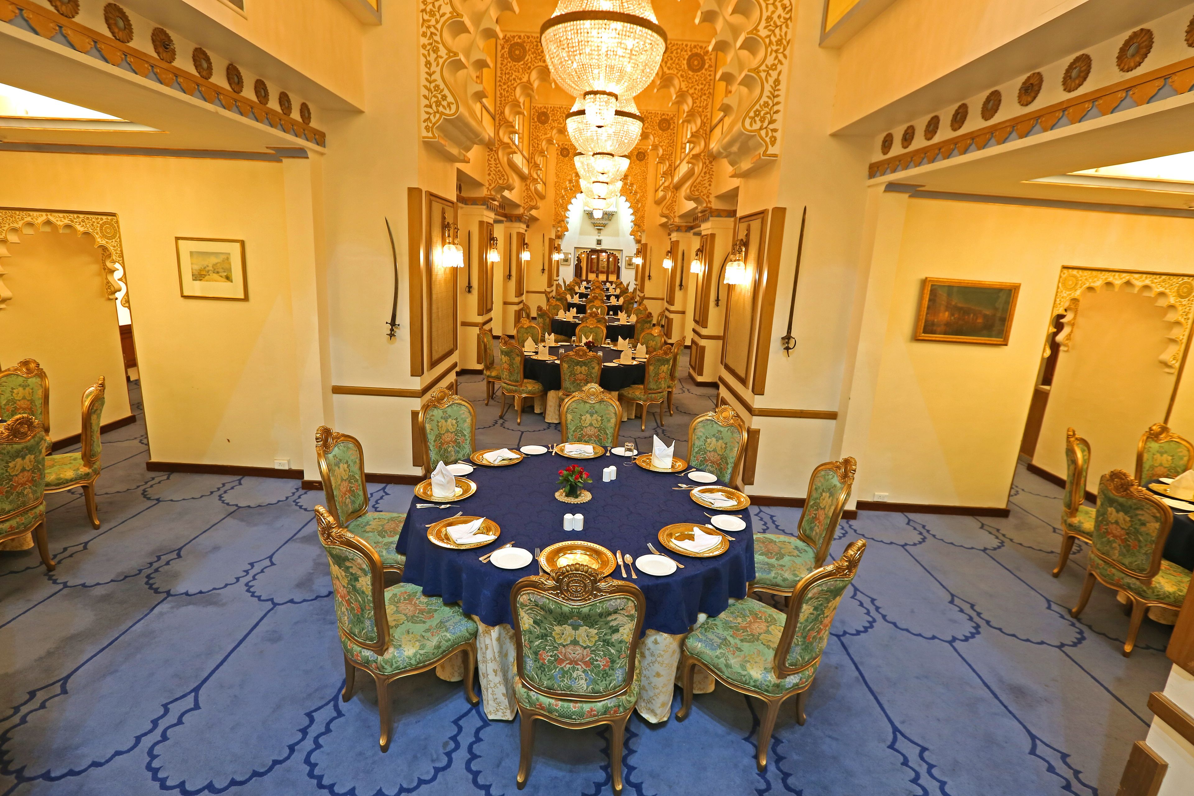 A formal dining room with a round table, ornate chairs, and a chandelier.