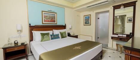 A hotel room with a large bed, a nightstand, a dresser, a mirror, and a painting on the wall.