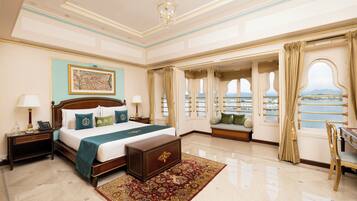A spacious bedroom with a large bed, a nightstand, a dresser, and a view of the sea through the windows.